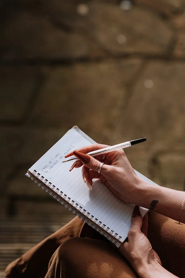 woman with long manicure taking notes in copybook